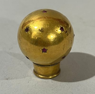 une boule dorée ornée d'étoiles, posée sur un fond blanc