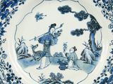 a blue and white plate with a picture of a woman and a dog
