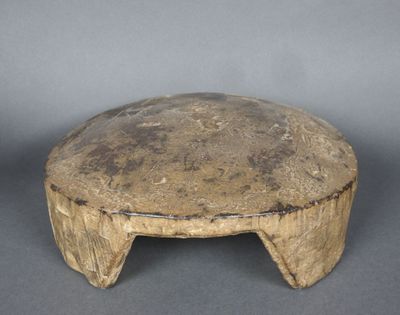 un vieux tabouret en bois posé sur une surface grise