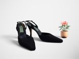 une paire de chaussures à talons hauts noires à côté d'une plante en pot