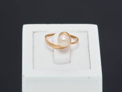a close up of a gold ring with a pearl in it