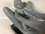 statue of a woman sitting on a man ' s back on a black base