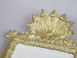 a mirror with a gold frame on a white wall