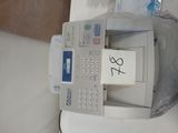une calculatrice posée sur un bureau, avec un bout de papier accroché dessus