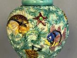 un vase vert orné de poissons, posé sur une table