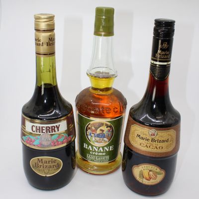 three bottles of liquor are lined up on a white surface