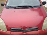 une voiture rouge garée sur le gravier