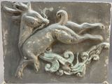 a stone plaque with a deer and a bird on it