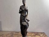 une statue représentant une femme tenant un bol posé sur une table