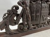 carved wood coat of arms of a man and woman holding a shield