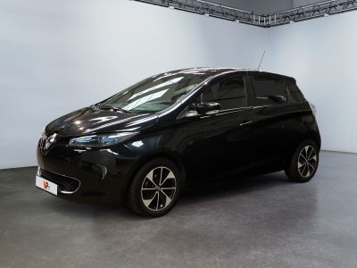 La voiture noire est garée dans une grande pièce aux murs blancs.