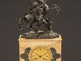 an antique clock with a bronze statue of a man on a horse on a marble base