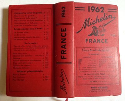 an old book with a red cover sitting on top of a table