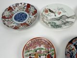 four plates with different designs on them sitting on a white surface