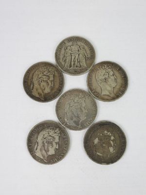 six different british coins sitting on top of each other on a white surface