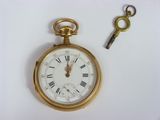 a gold pocket watch and a key on a white surface