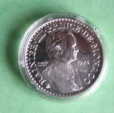 a close up of a coin in a plastic container on a green surface