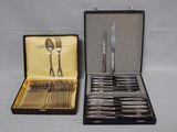 deux sets d'argenterie dans un coffret sur une table