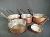 five pots and pans on a table with a black background