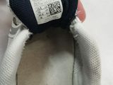someone is holding a pair of white shoes with a black and white label