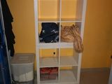 une étagère blanche sur laquelle sont posés des vêtements, dans une pièce jaune