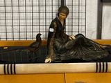 une statue représentant une femme assise sur un livre