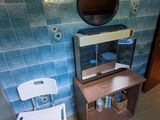 une petite salle de bains avec un mur carrelé de bleu et une chaise blanche