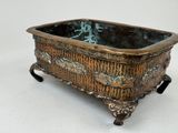 a bronze planter that is sitting on a white surface