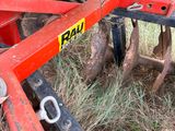 a red and green plow sitting next to a tree