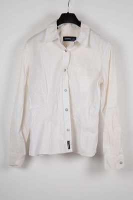the white shirt is hanging on a hanger on the wall