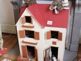 une maison de poupées sur le toit de laquelle sont assis un chien et un chat