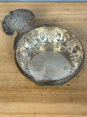 un plateau en argent orné de raisins, posé sur une table en bois