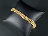 a gold chain bracelet on a pillow on a black background