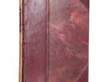 an old book with a red leather cover on a white background