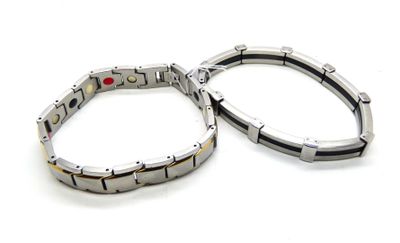 pair of stainless steel bracelets with red stones on white background