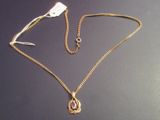 a gold necklace with a pink stone on it