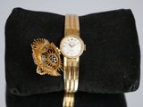 a gold bracelet and a watch sitting on a black bag