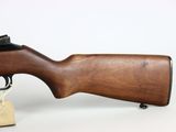 a rifle with a wooden barrel on a stand on a white surface
