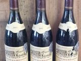 three bottles of wine are lined up on a wooden shelf
