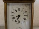a small brass clock with roman numerals on the face