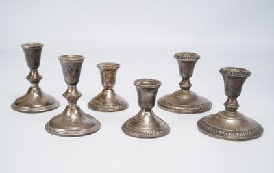 several silver candlesticks are lined up on a white surface