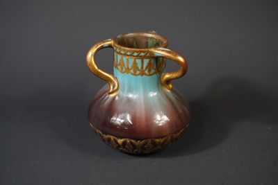 a brown and blue vase sitting on a table