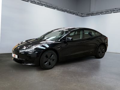 La Tesla Model 3 noire est garée dans une grande pièce.