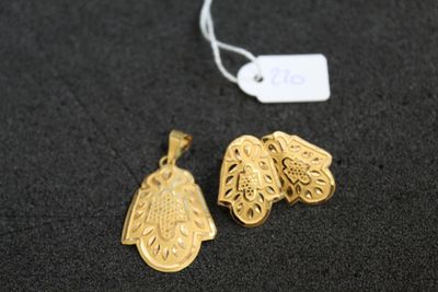 deux pendentifs en or posés sur une surface noire, accompagnés d'une étiquette de prix