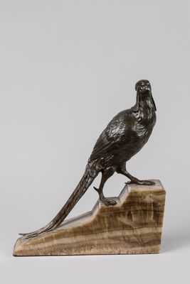 une statue représentant un oiseau perché sur un bloc de bois