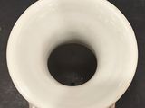 a white vase with a hole in it on a table