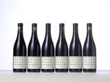 six bottles of wine lined up in a row on a table
