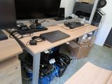 a desk with a laptop, monitor, keyboard and other electronics on it