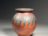un vase orange et noir posé sur une table blanche