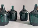 three green glass bottles with a wooden stopper sit on a white surface